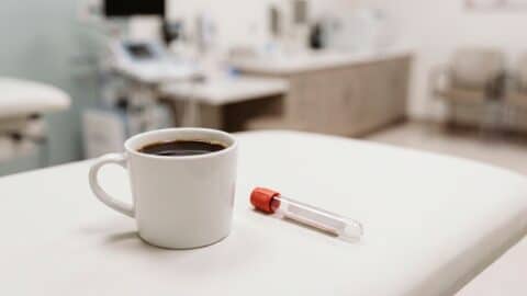 Taza de café negro junto a un tubo para análisis de sangre en una clínica.