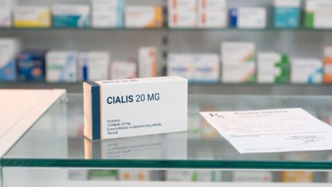 Caja de Cialis 20 mg sobre el mostrador de cristal de una farmacia junto a una receta medica oficial