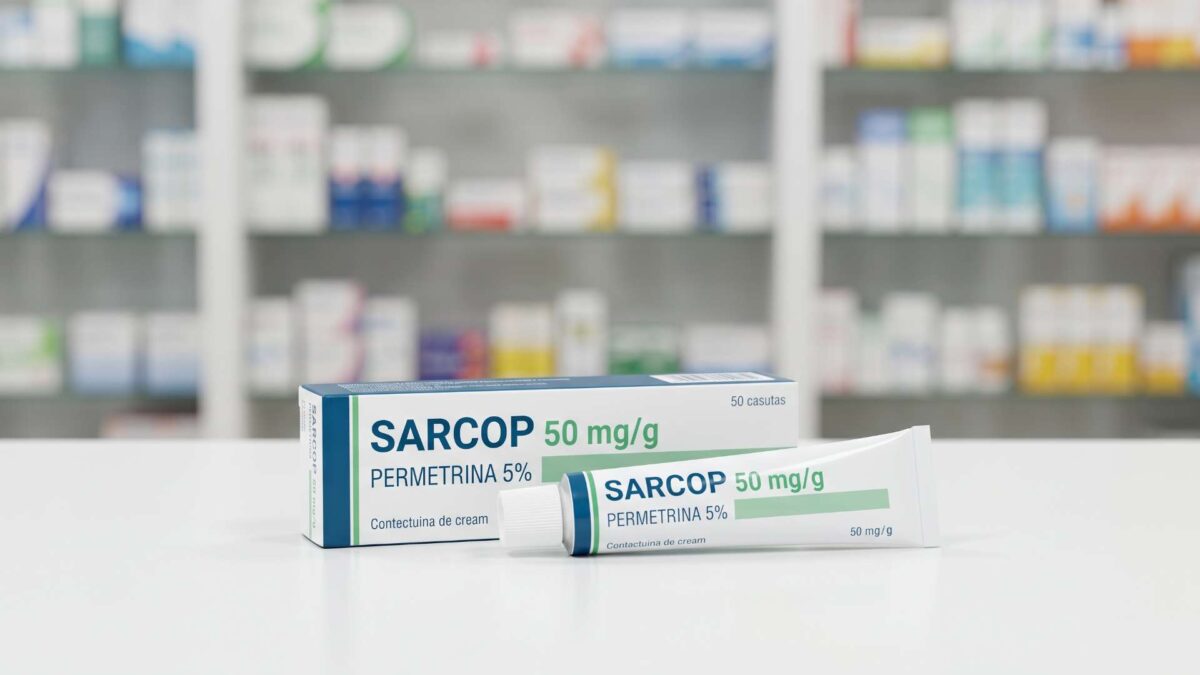 Caja y tubo de crema Sarcop permetrina 50 mg sobre el mostrador de una farmacia