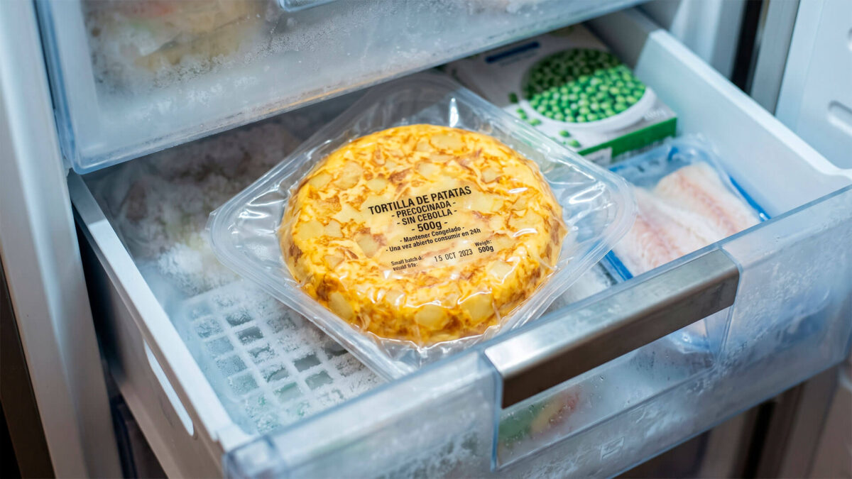 Tortilla de patatas envasada precocinada guardada dentro de un congelador doméstico con escarcha.